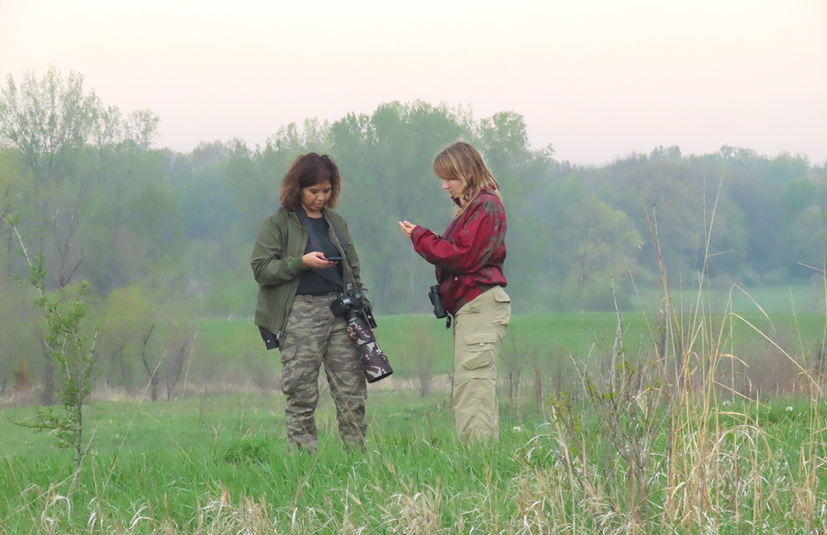 Lakshmi Balasubramanian and Toni Proescholdt checking Henslow's Sparrow call on phone while in the field by Ted Floyd